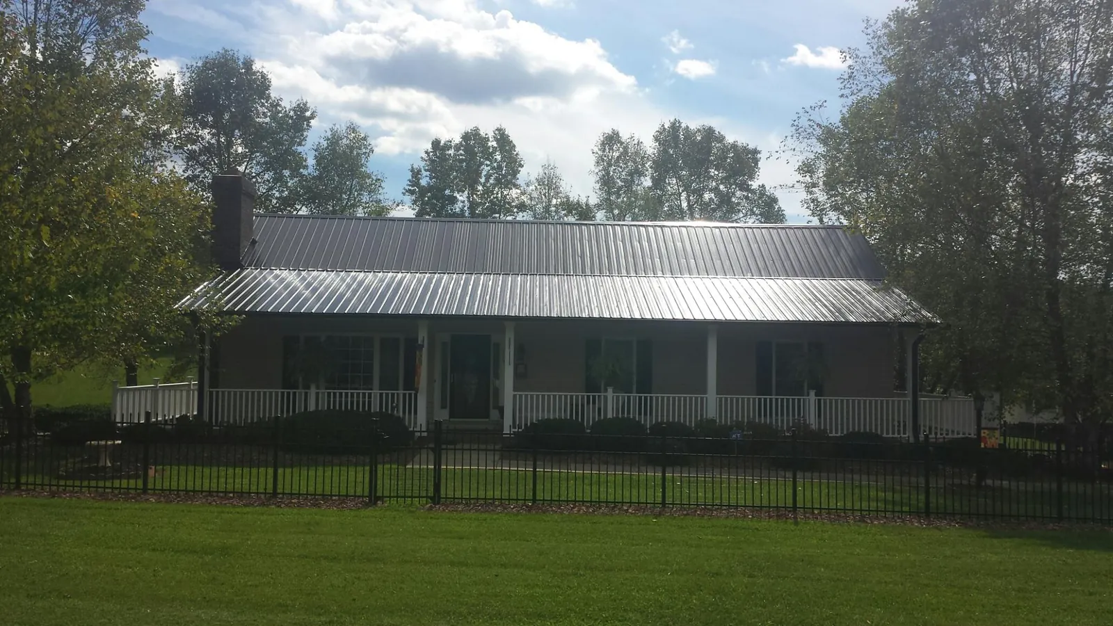 Gray metal roof on a brick ranch with a full width front porch — Gutter Guard Installation work by our crew in Gray